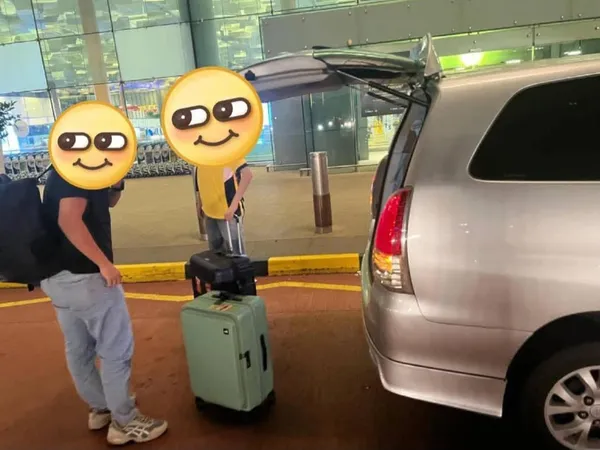 Customers with luggage beside a silver van at a terminal building
