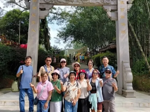 A group posing under a stone archway with Chinese inscriptions at a temple site