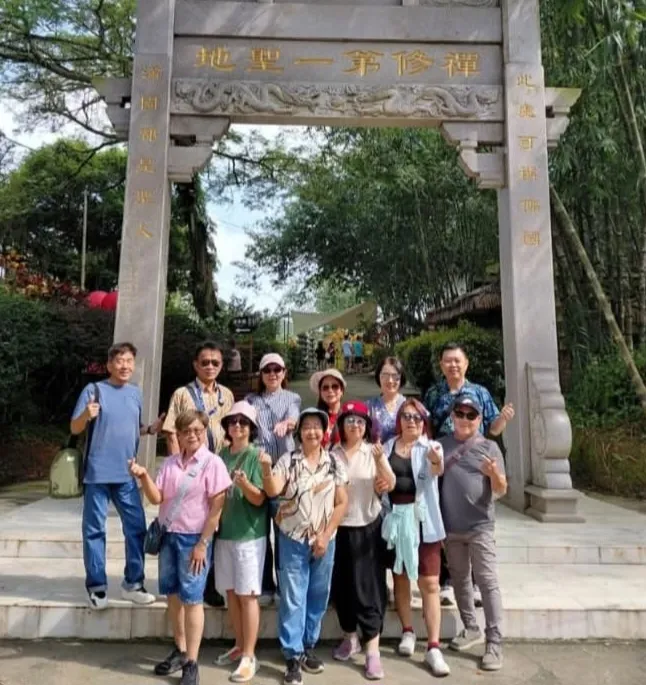 A group posing under a stone archway with Chinese inscriptions at a temple site