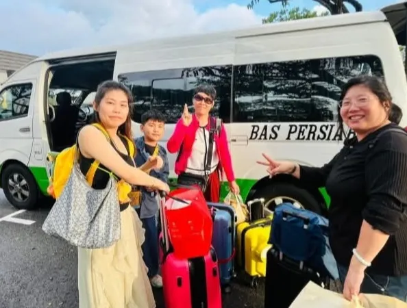 A family with luggage beside a Bas Persiaran tour van