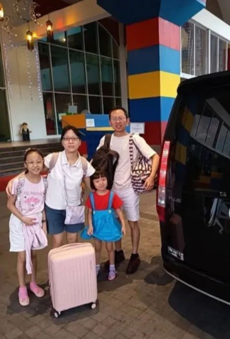 A family of four outside the Legoland Hotel entrance beside a black MPV