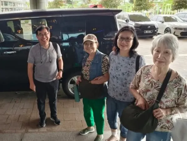 A group of four beside a black MPV in a car park