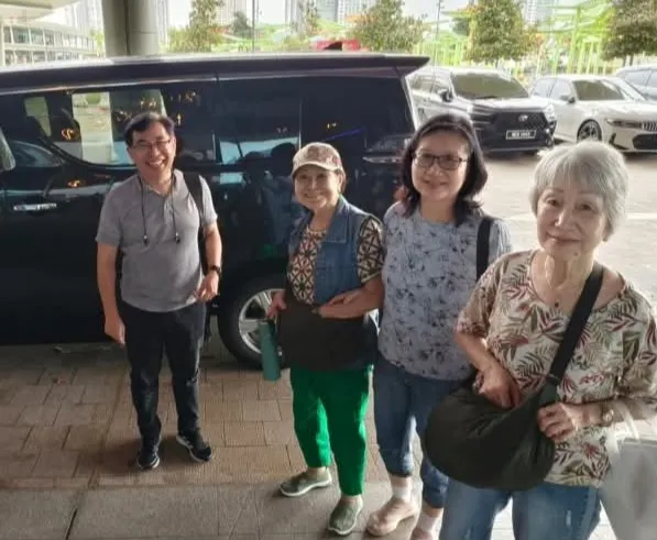 A group of four beside a black MPV in a car park