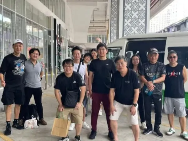 A group of customers with their chauffeur van outside a building in Malaysia