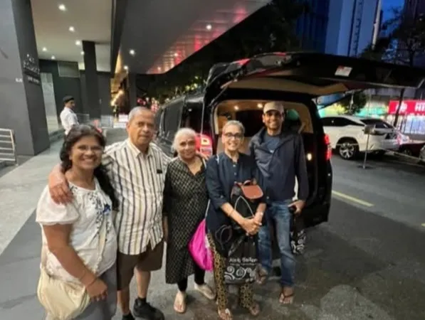 A group posing beside a black van outside a hotel entrance at night