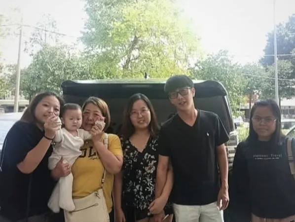 A family with a baby posing beside a black van