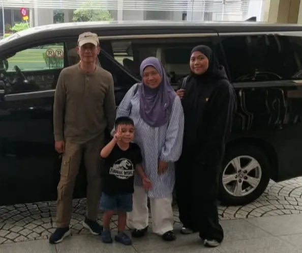 A family of four beside a black van in a car park