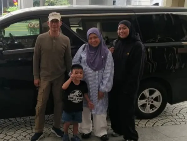 A family of four beside a black van in a car park