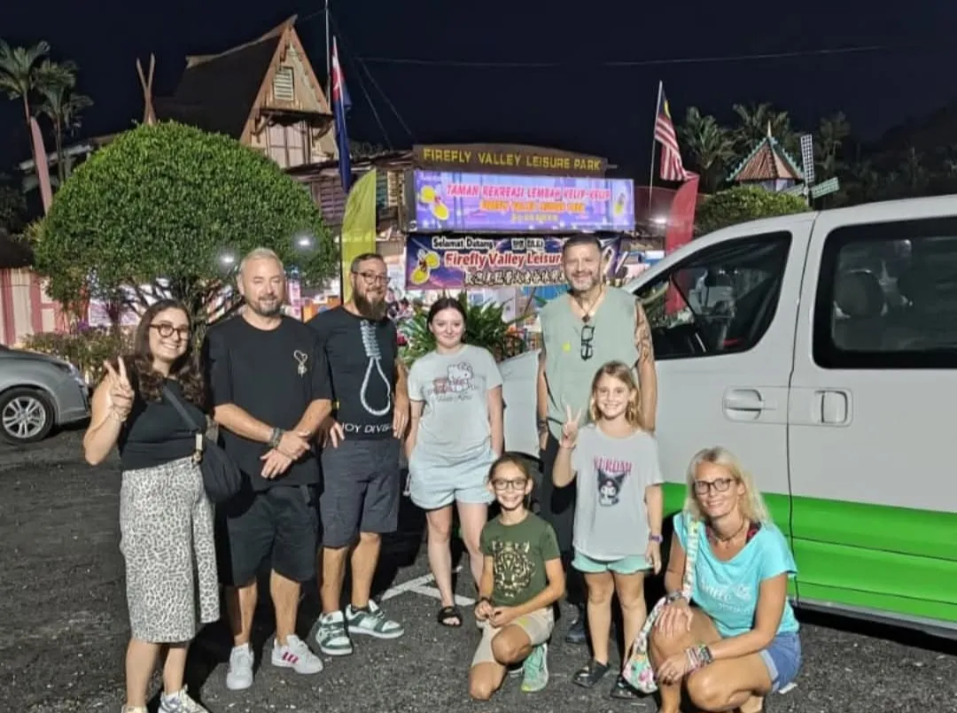 An international family posing with their chauffeur van at Firefly Valley Leisure Park at night