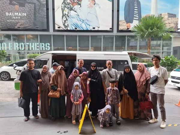A large family group posing beside a white van outside a shopping mall