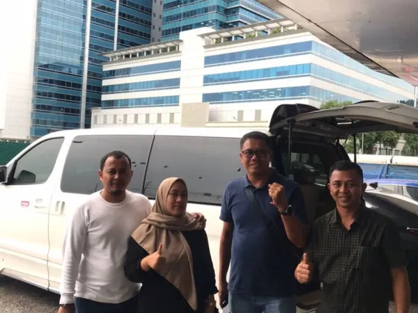 A group posing beside a white MPV with Singapore high-rise buildings in the background