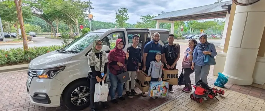 A group with shopping bags posing beside a white van at a rest area