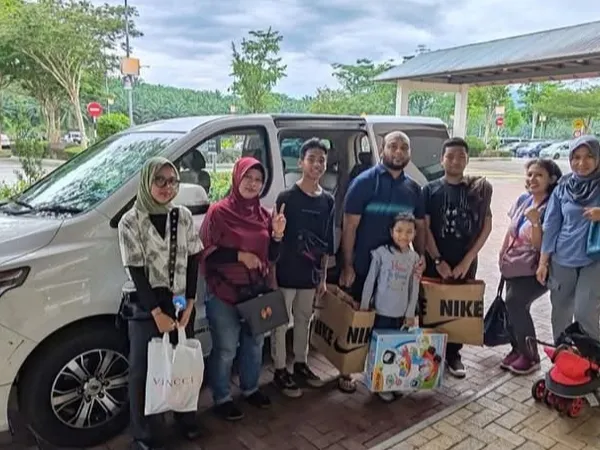 A group with shopping bags posing beside a white van at a rest area