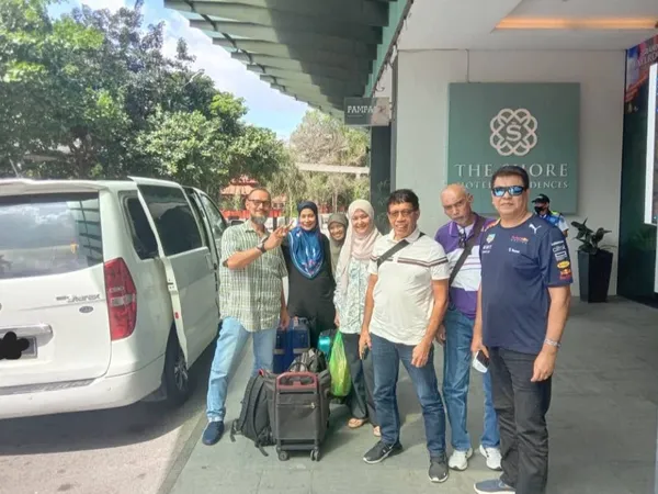 A group posing with their white Hyundai Starex chauffeur van outside The Shore Hotel Residences