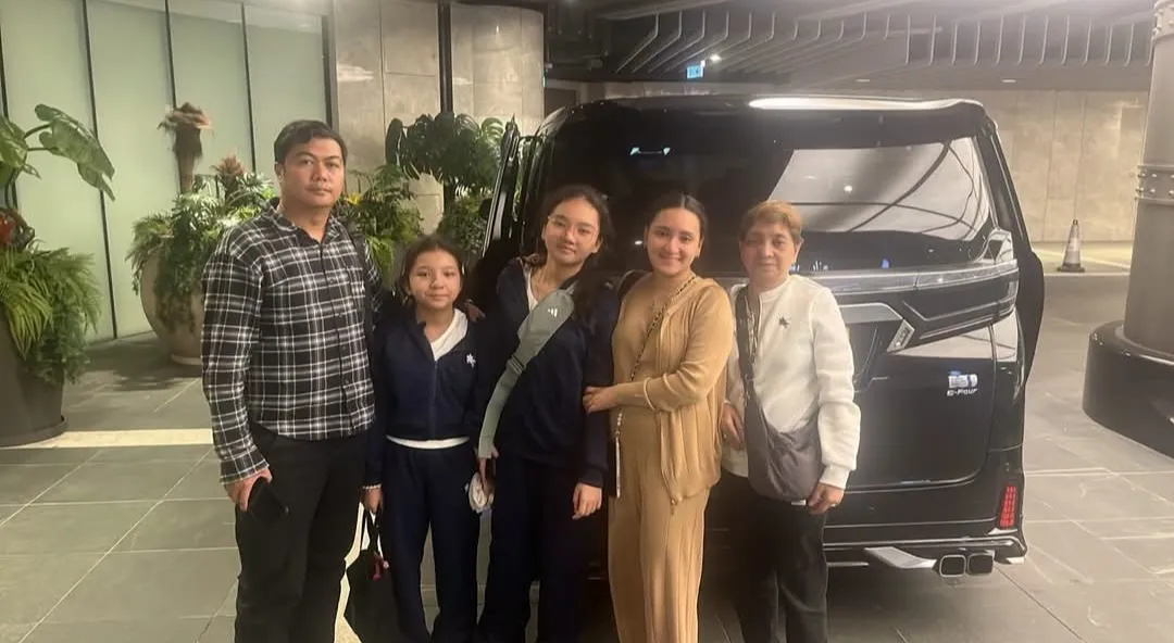 A family posing beside a black Toyota Alphard in a hotel lobby