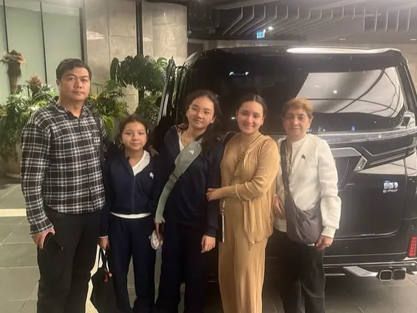 A family posing beside a black Toyota Alphard in a hotel lobby