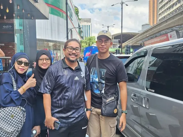 A group posing beside a silver van outside the WOLO Hotel in Kuala Lumpur