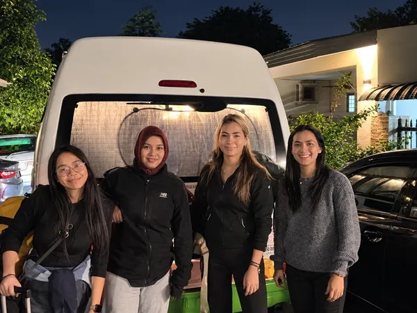 Four customers posing beside a white van at dusk