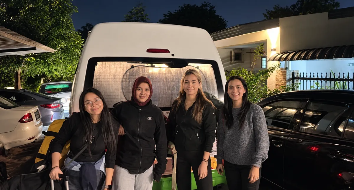 Four customers posing beside a white van at dusk