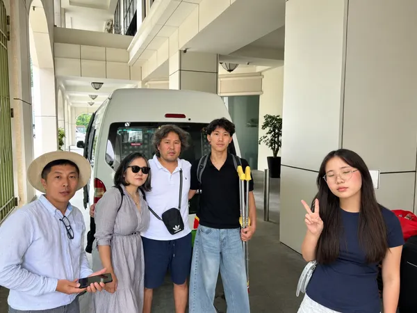 A group posing beside a white van outside a hotel entrance