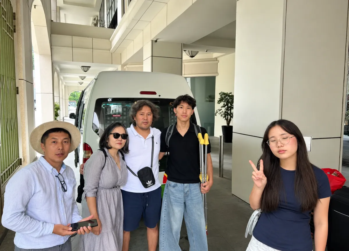 A group posing beside a white van outside a hotel entrance