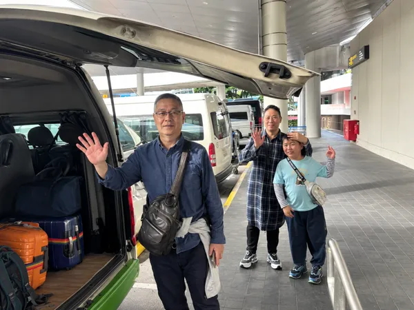Customers waving beside a van loaded with luggage at a terminal