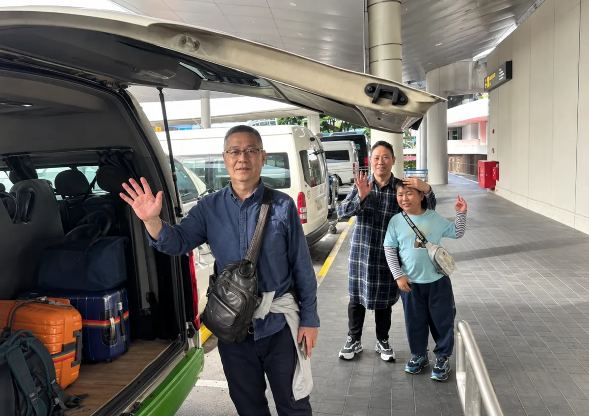 Customers waving beside a van loaded with luggage at a terminal
