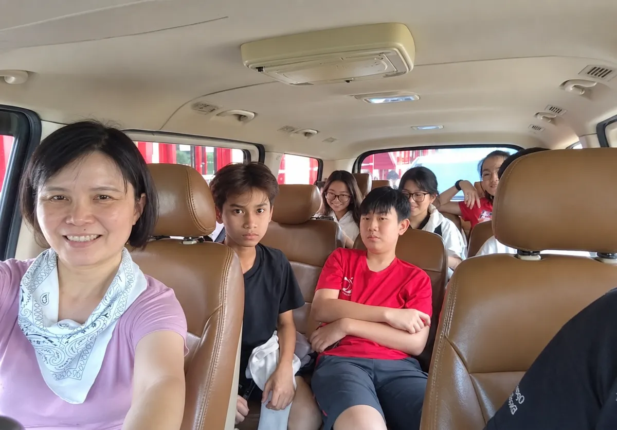 A family taking a selfie inside the van with children seated behind