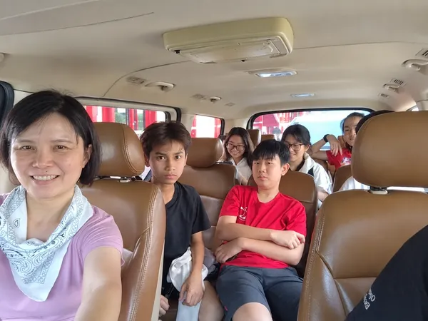 A family taking a selfie inside the van with children seated behind
