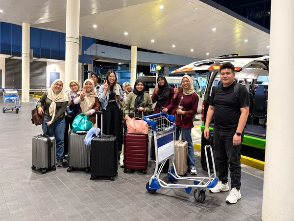 A group with a luggage cart at an airport terminal at night
