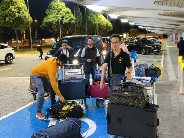 A group loading luggage onto an airport trolley at night