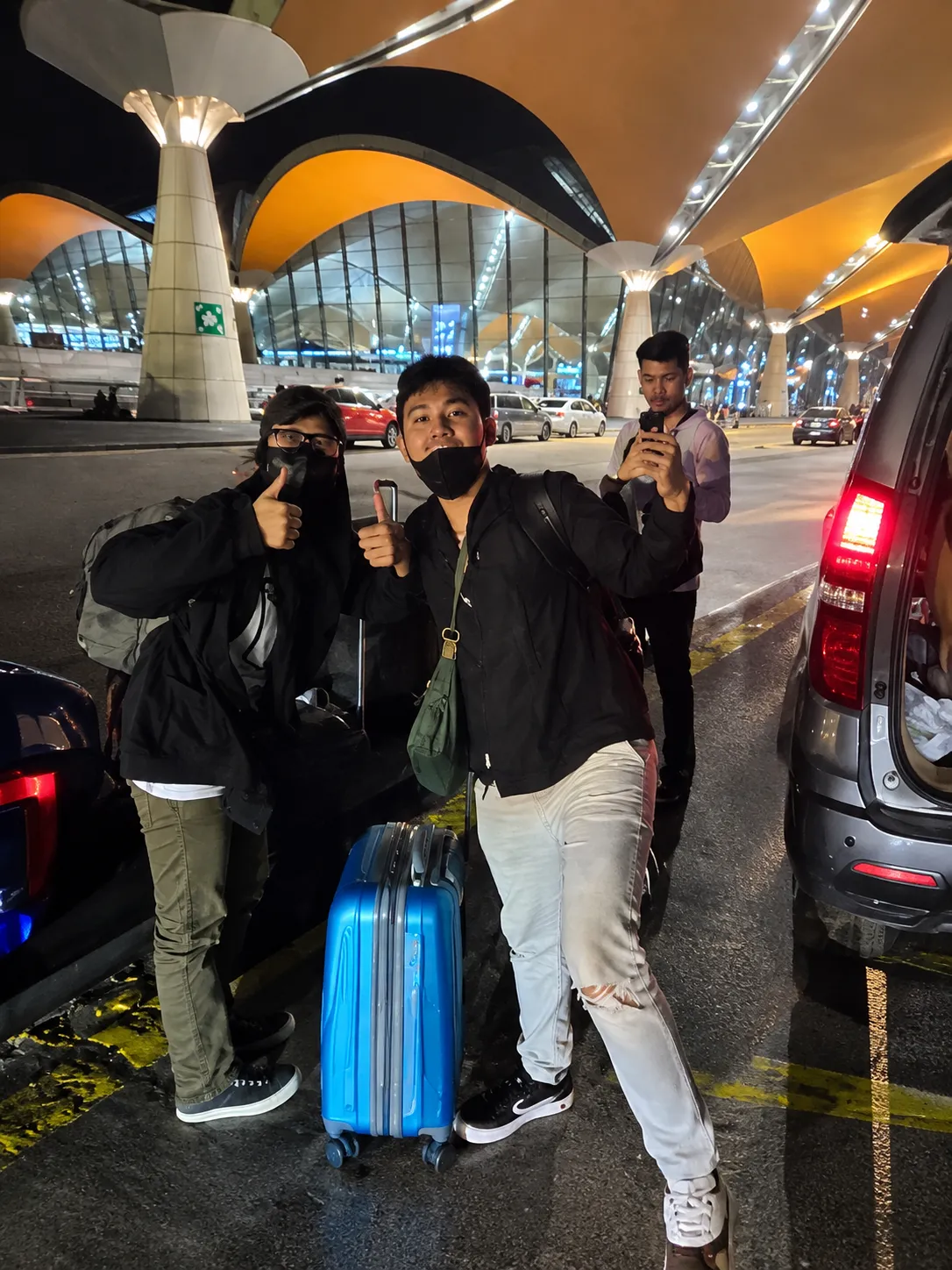 Two customers with luggage at Kuala Lumpur International Airport at night